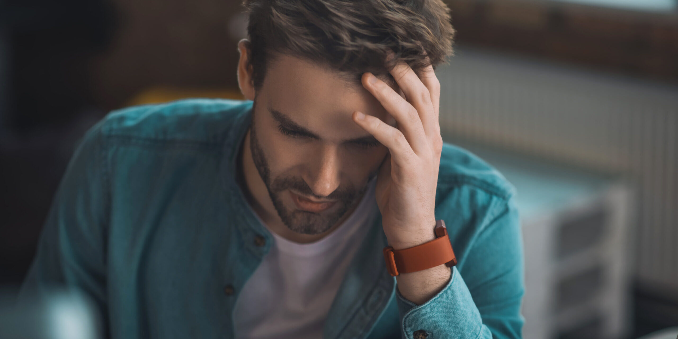 Handsome sad young man touching his head Man at work